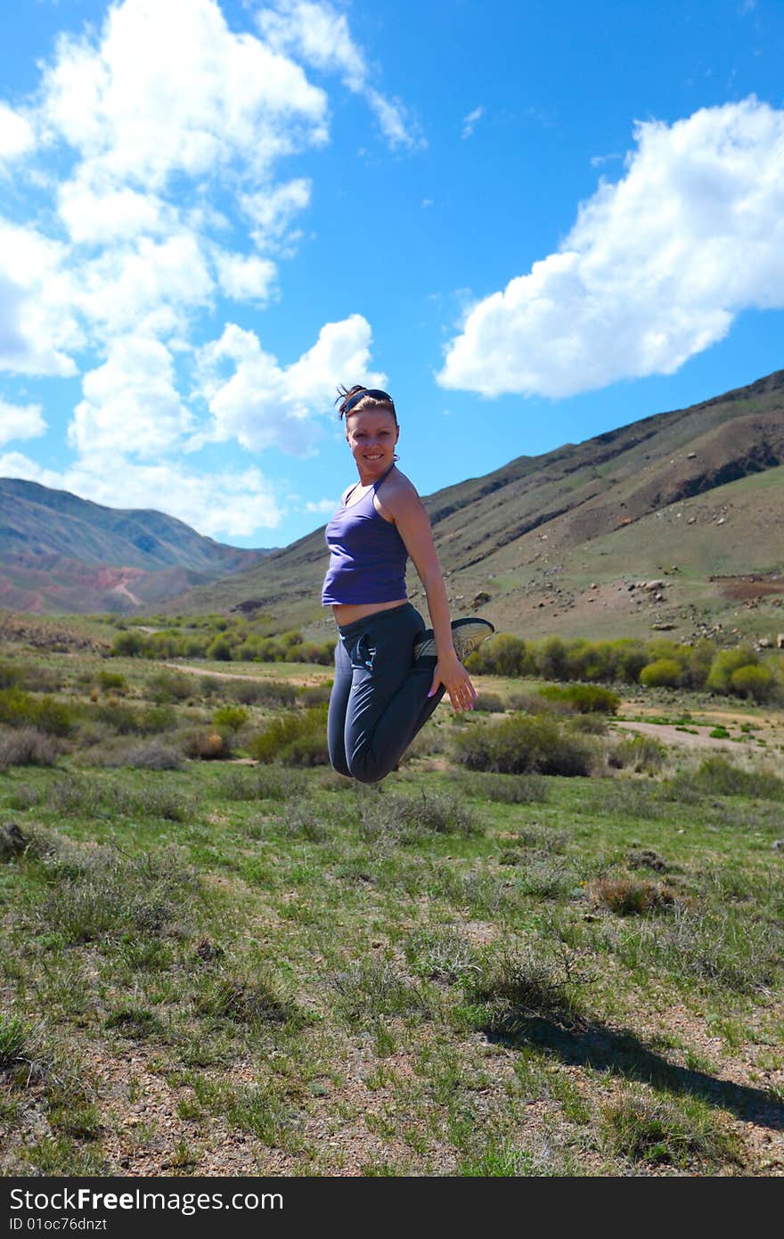 The girl jumping upwards against mountains. The girl jumping upwards against mountains