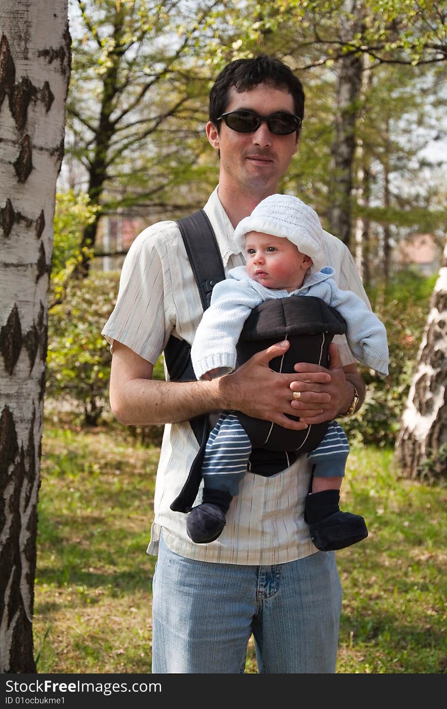 Father with a little child in a sling standing by a birch tree. Father with a little child in a sling standing by a birch tree