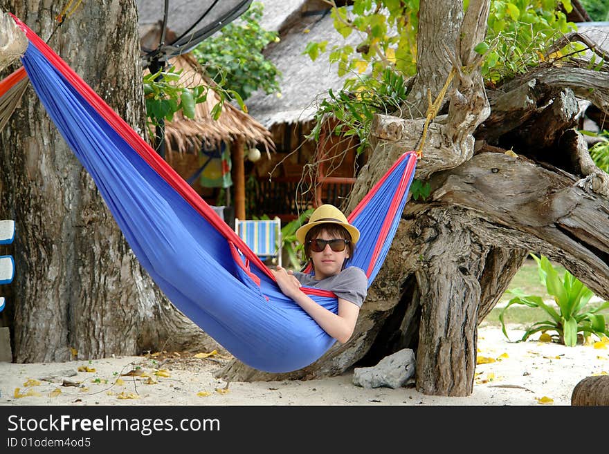 Boy In A Hat And Sunglasses In A Blue Hammock