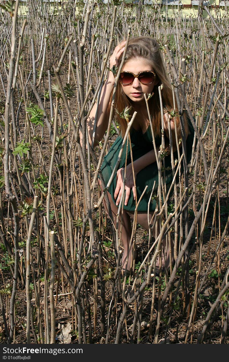 Girl sitting among bushes in a na abandoned garden