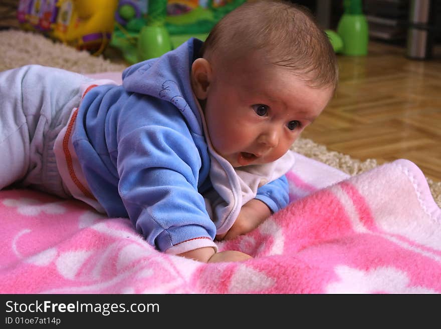 Small young child is playing on the blanket. Small young child is playing on the blanket