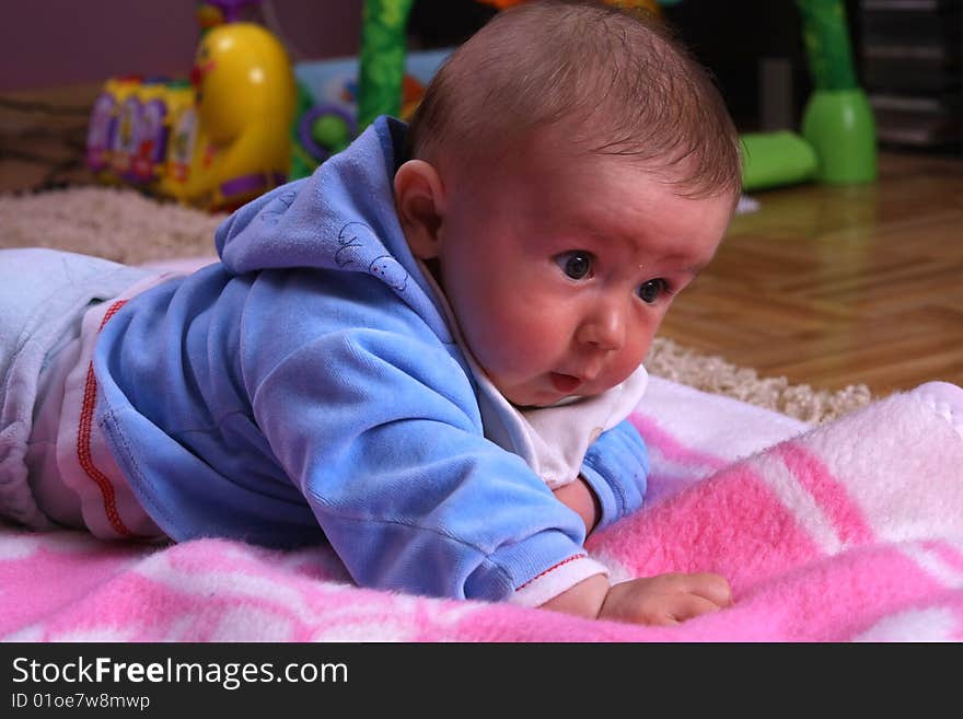 Small young child is playing on the blanket. Small young child is playing on the blanket