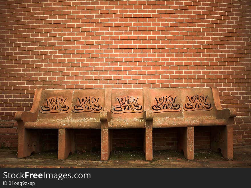 A stone bench in front of a brick wall