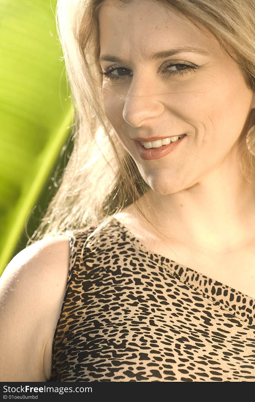 A very pretty and young blond brazilian woman wearing a leopard skin like blouse, in front of a bright green banana leaf. A very pretty and young blond brazilian woman wearing a leopard skin like blouse, in front of a bright green banana leaf.