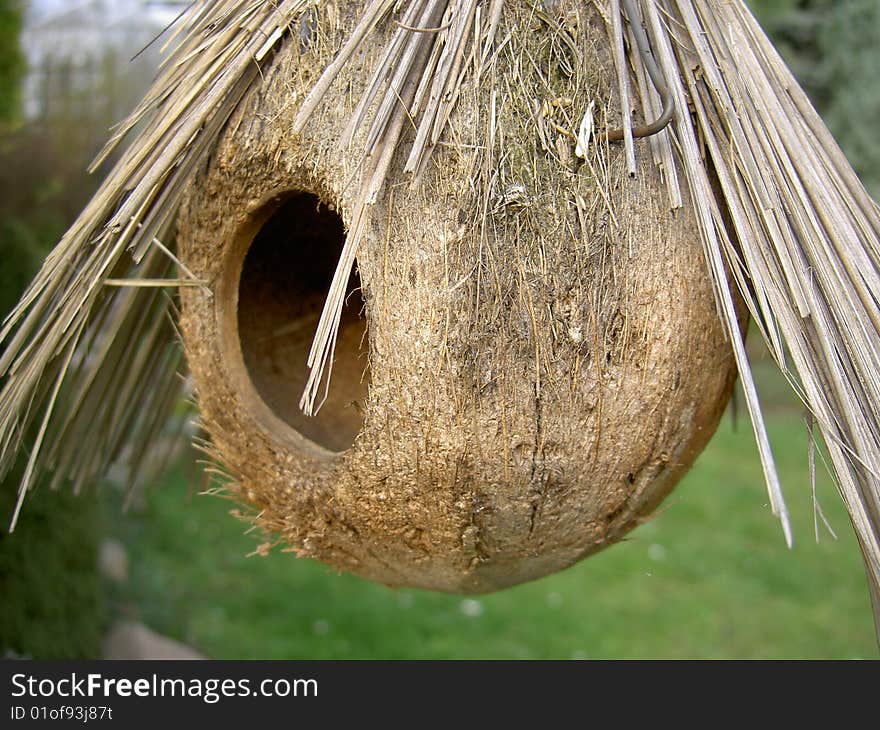 Round bird box with straw shelter in garden. Round bird box with straw shelter in garden