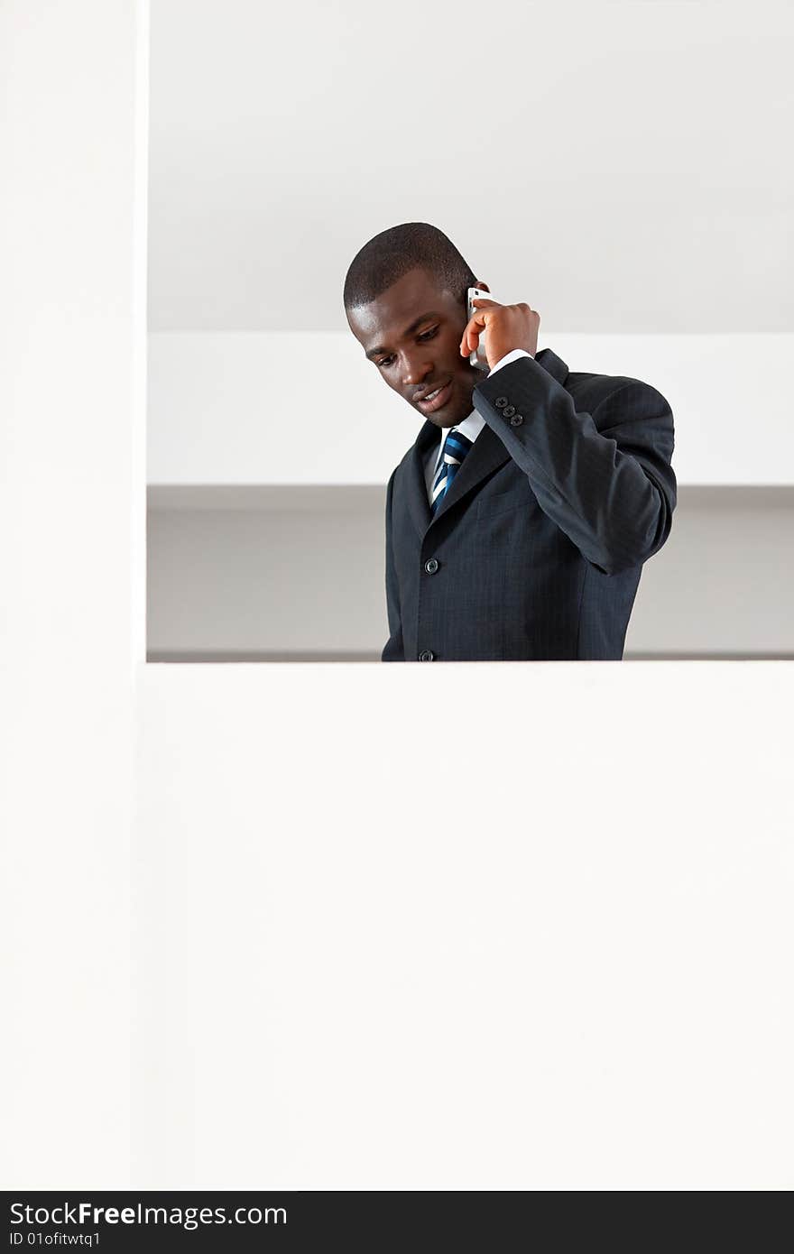 Young adult afro-american businessman talking on the phone indoors. Copy space