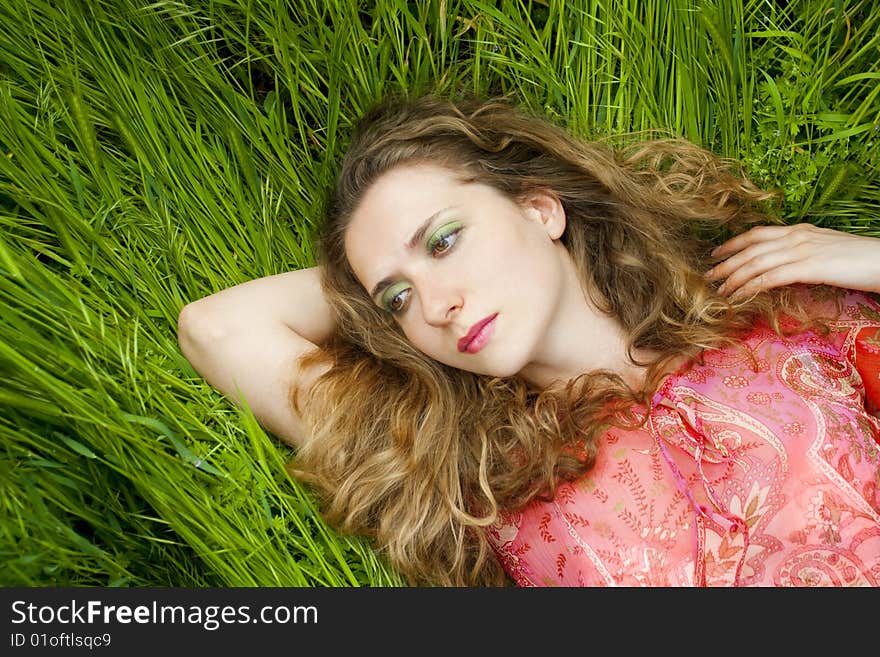 Beautiful woman lying on green grass relaxing in summer. Beautiful woman lying on green grass relaxing in summer