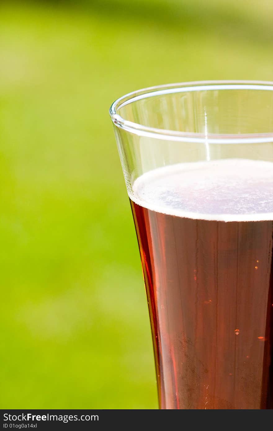 Glass beer on green background