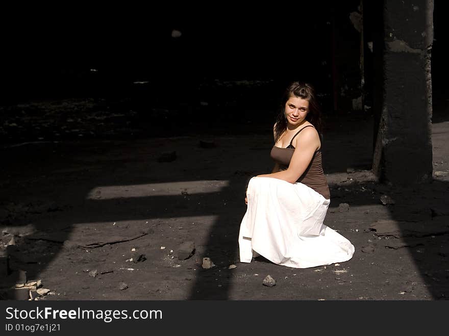 Young woman in a white dress, in an old black factory. Young woman in a white dress, in an old black factory