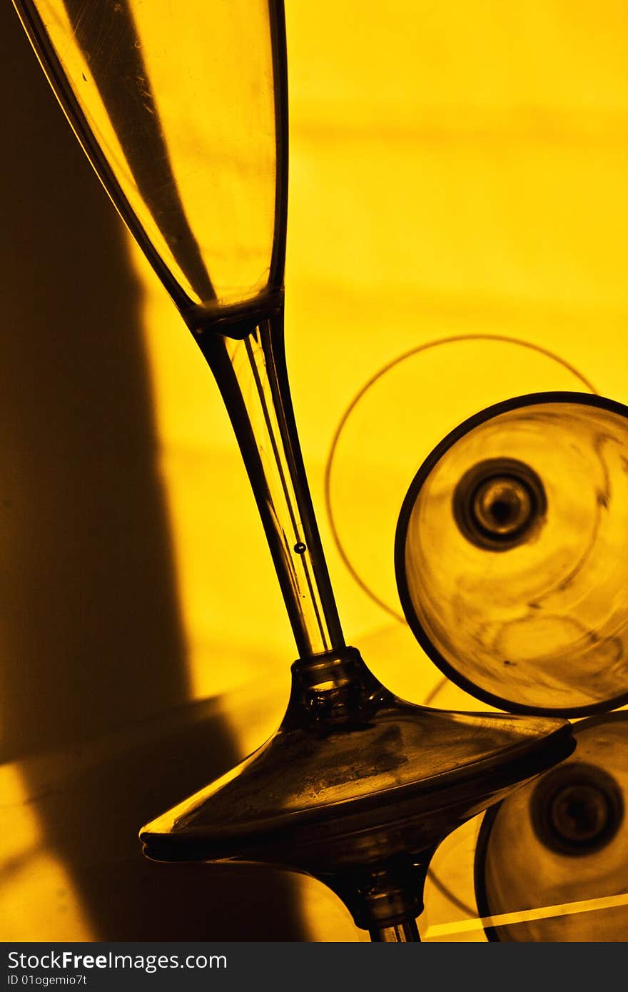 Elegant wine and champagne glasses against a back lit yellow background. Elegant wine and champagne glasses against a back lit yellow background