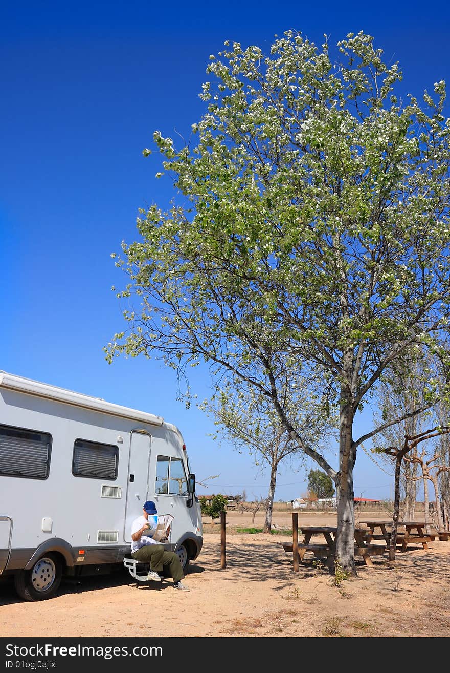 Man sitting on his motorhome steps, looking at a road map