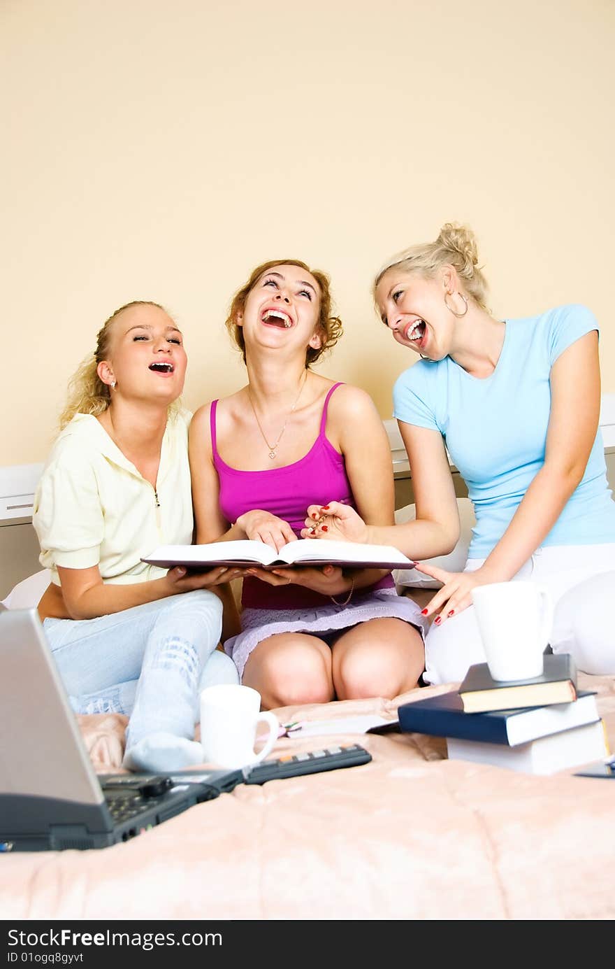 Three happy laughing students at home on the bed. Three happy laughing students at home on the bed