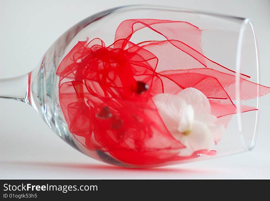 Red ribbon and white flower inside a wine glass. Red ribbon and white flower inside a wine glass