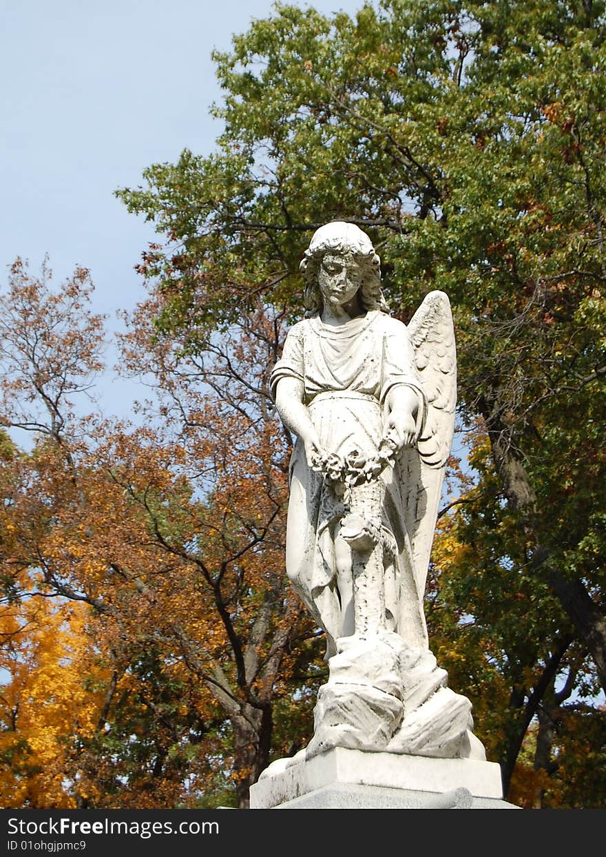 Sculpture of angel with fall trees in background. Sculpture of angel with fall trees in background