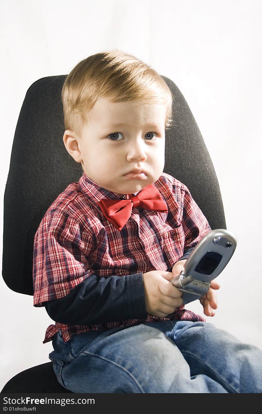 Little boy sitting in the armchair and the cell phone holds. Little boy sitting in the armchair and the cell phone holds