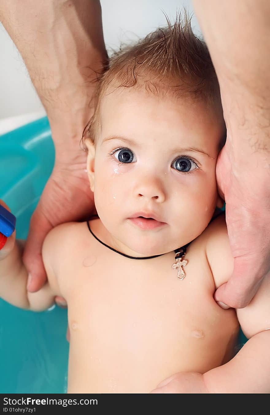 Baby bathes in a bathroom on hands of the father