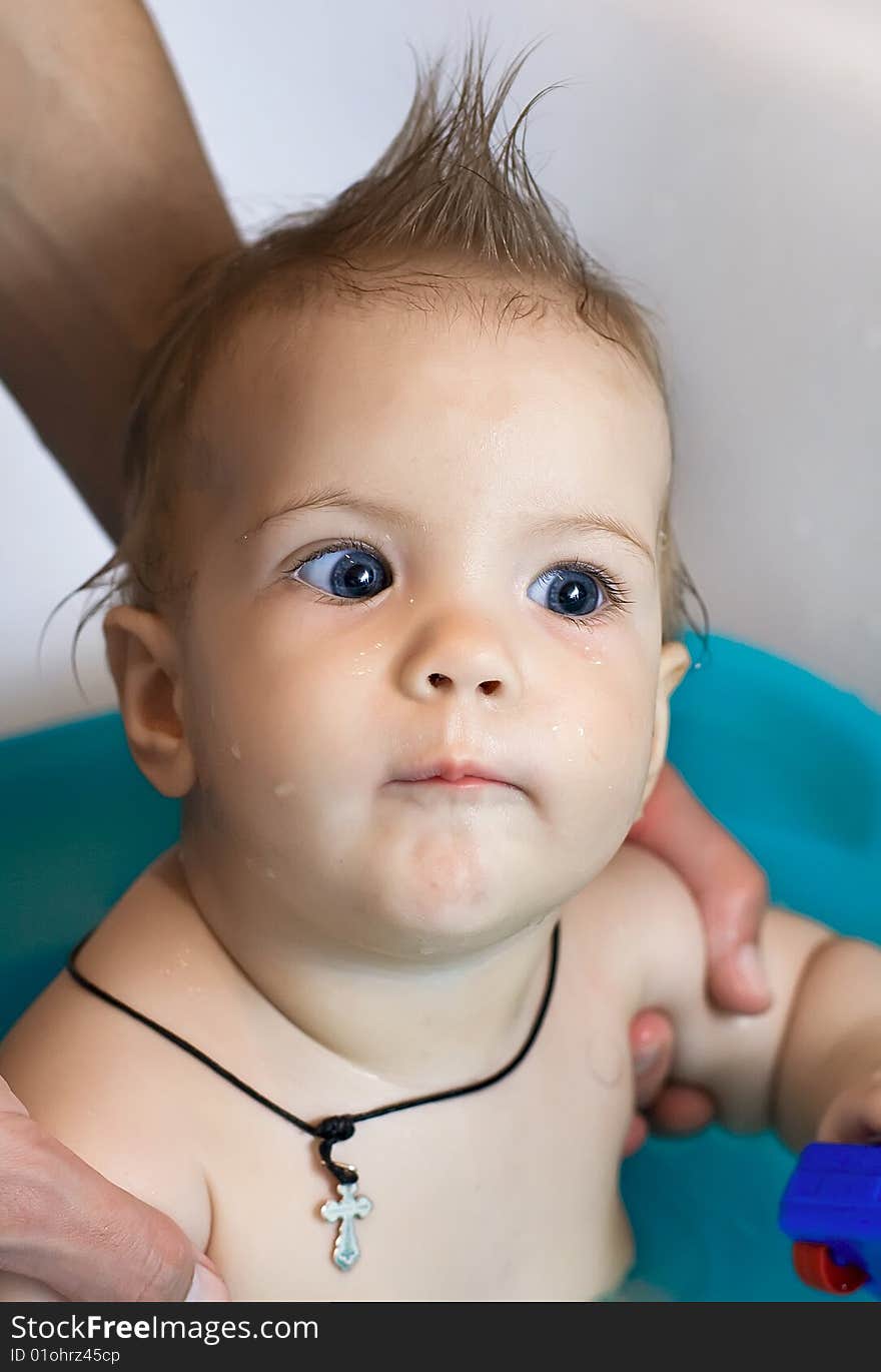 Baby bathes in a bathroom on hands of the father