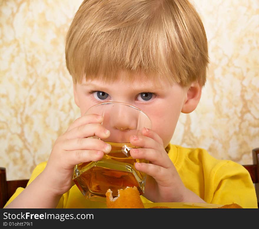 The hungry little boy drinks a glass with juice. The hungry little boy drinks a glass with juice