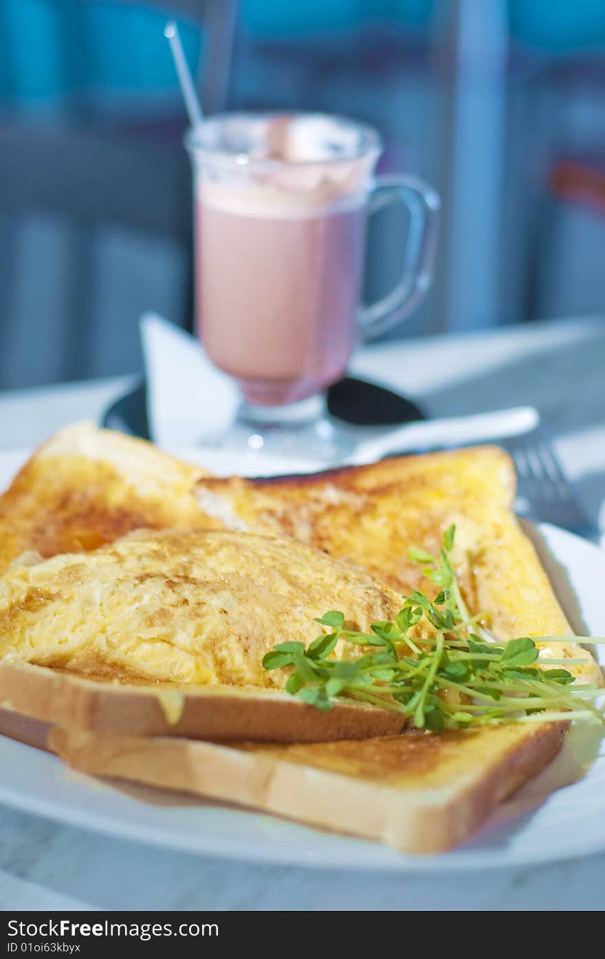 A delicious breakfast set of french toast topped with garnishing, complete with a cup of hot chocolate drink.