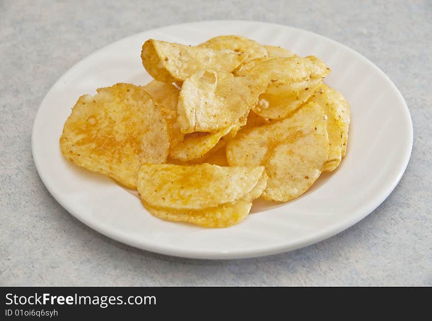 Barbeque flavored potato chips laid out nicely on a porcelain plate.