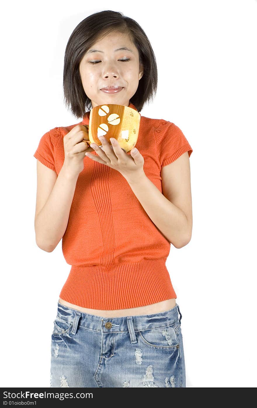 Charming Asian girl holding big mug with tea. Girl with kind face expression, wearing orange sweater. Charming Asian girl holding big mug with tea. Girl with kind face expression, wearing orange sweater.