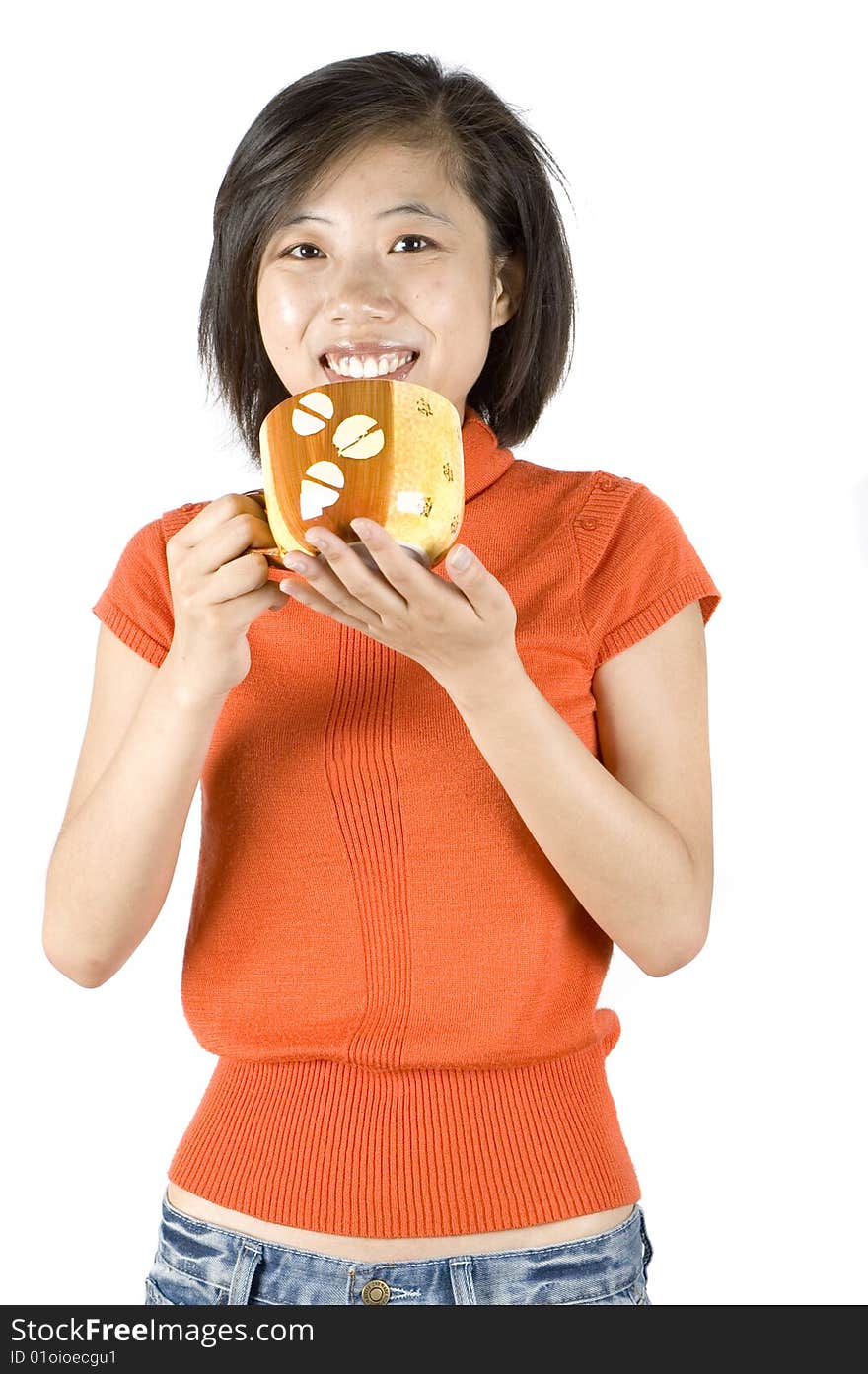 Charming Asian girl holding big mug with tea. Girl with kind face expression, wearing orange sweater. Charming Asian girl holding big mug with tea. Girl with kind face expression, wearing orange sweater.