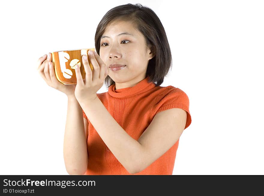 Charming Asian girl holding big mug with tea. Girl with kind face expression, wearing orange sweater. Charming Asian girl holding big mug with tea. Girl with kind face expression, wearing orange sweater.