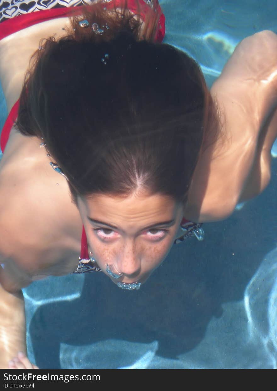 A young girl swimming underwater and blowing bubbles, ready to surface. A young girl swimming underwater and blowing bubbles, ready to surface.