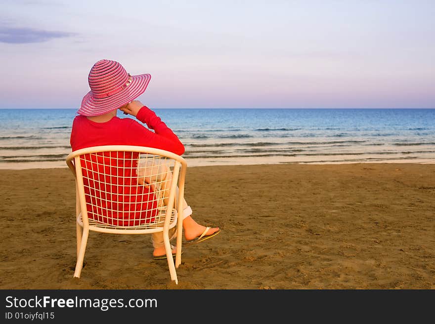 Lonely young woman near the ocean at sunrise time