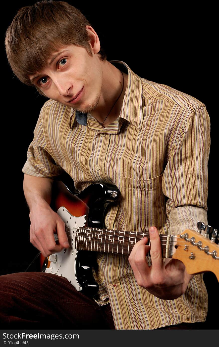 Young musician playing electric guitar isolated on black. Young musician playing electric guitar isolated on black