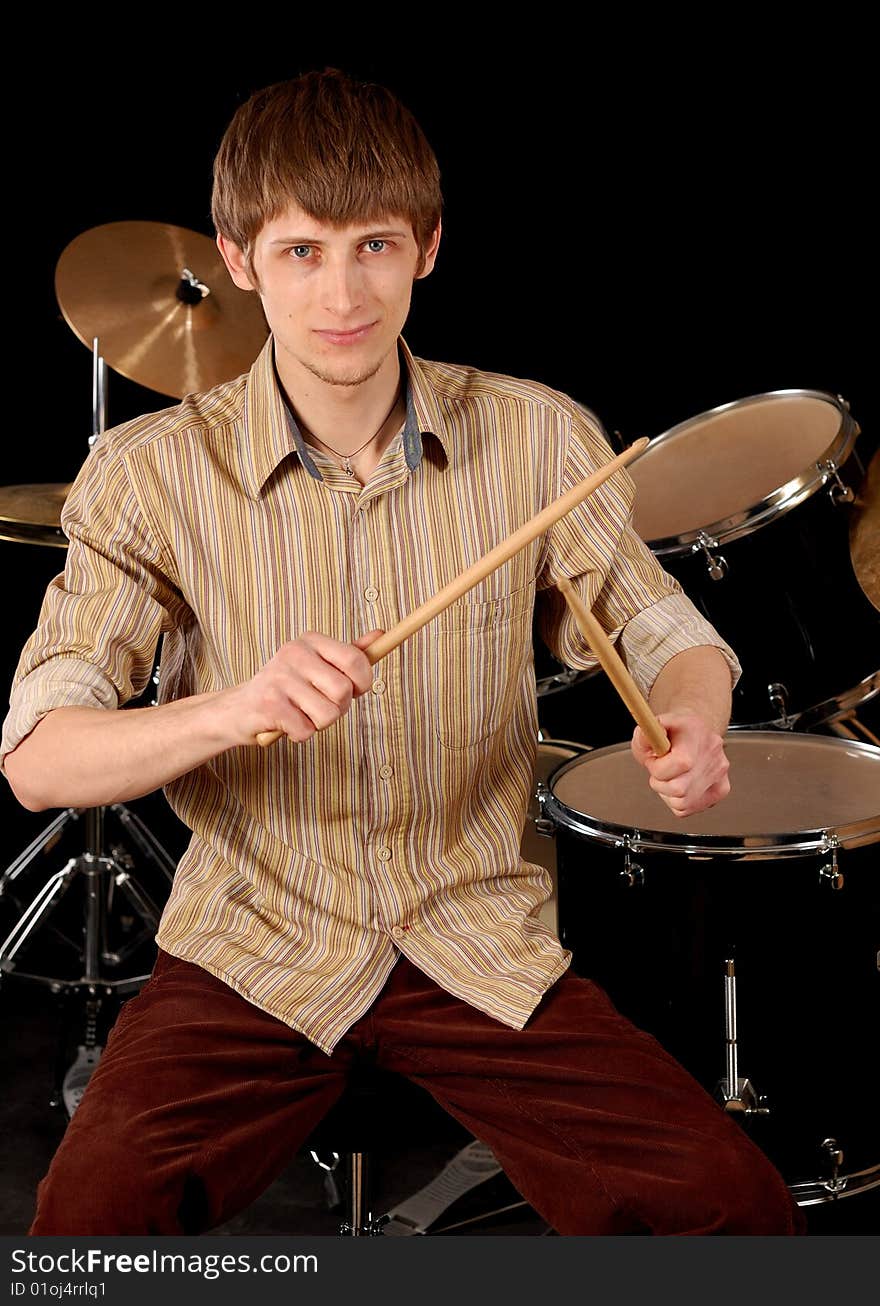 Young musician playing drums isolated on black. Young musician playing drums isolated on black.