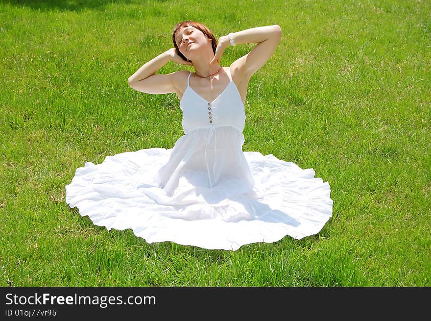 Beautiful young woman sitting on the grass. Beautiful young woman sitting on the grass.