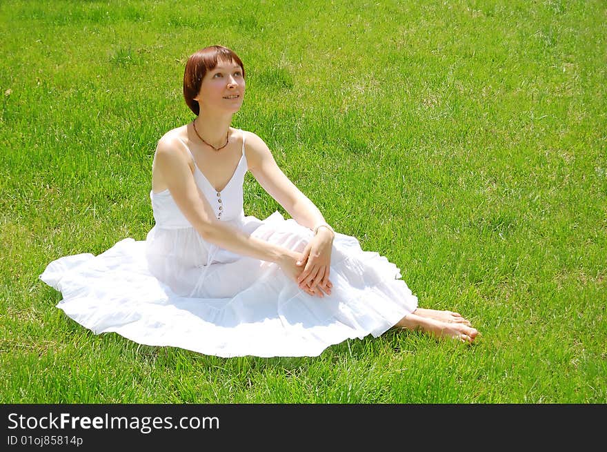 Beautiful young woman sitting on the grass. Beautiful young woman sitting on the grass.