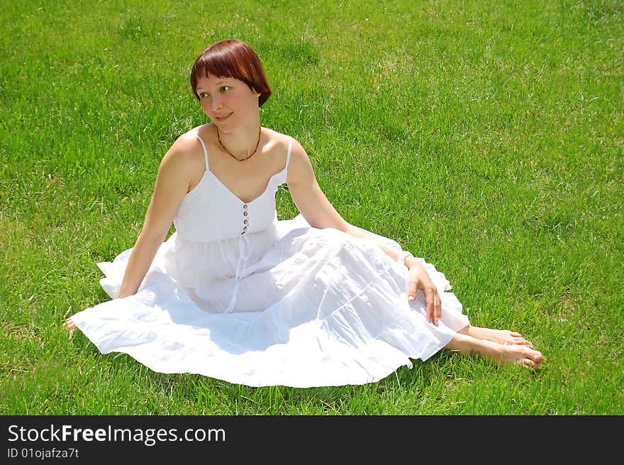 Beautiful young woman sitting on the grass. Beautiful young woman sitting on the grass.