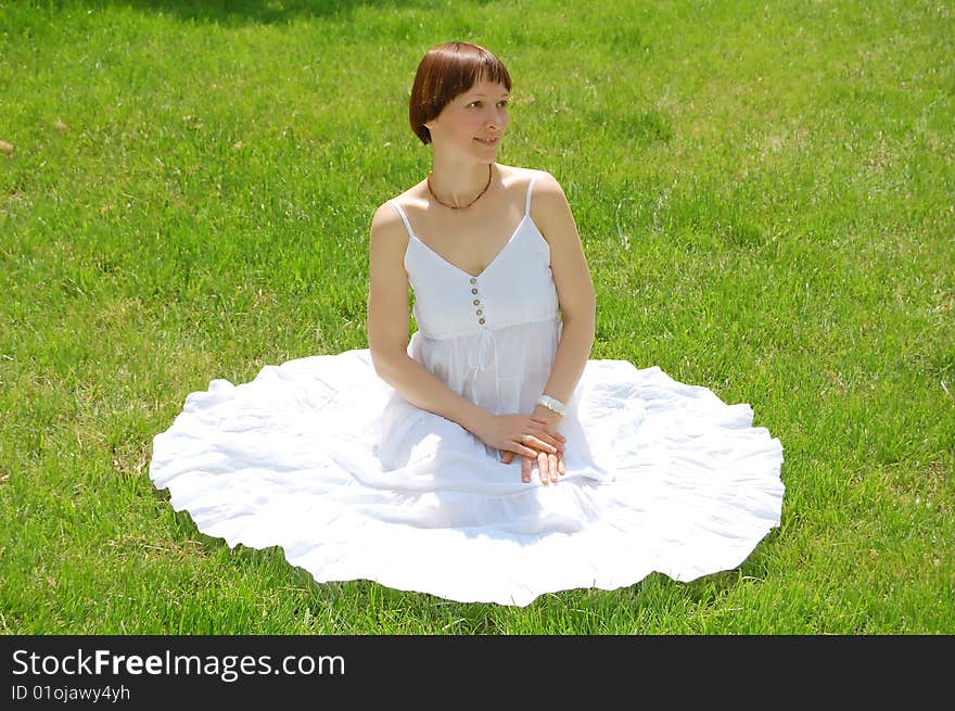 Beautiful young woman sitting on the grass. Beautiful young woman sitting on the grass.