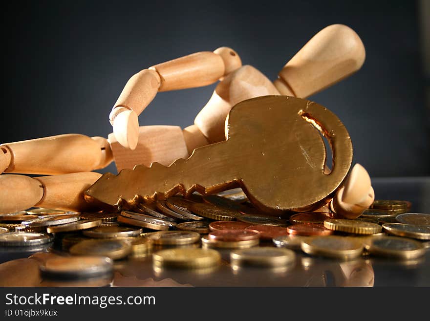 Wooden man, golden key and lot of coins. Wooden man, golden key and lot of coins.