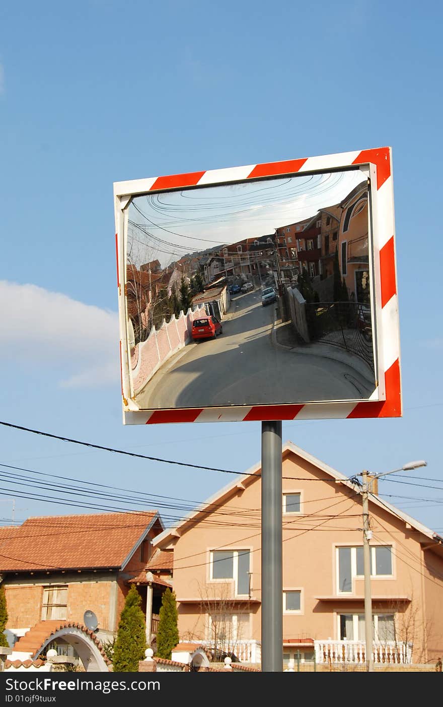 Street mirrored in traffic mirror over blue sky