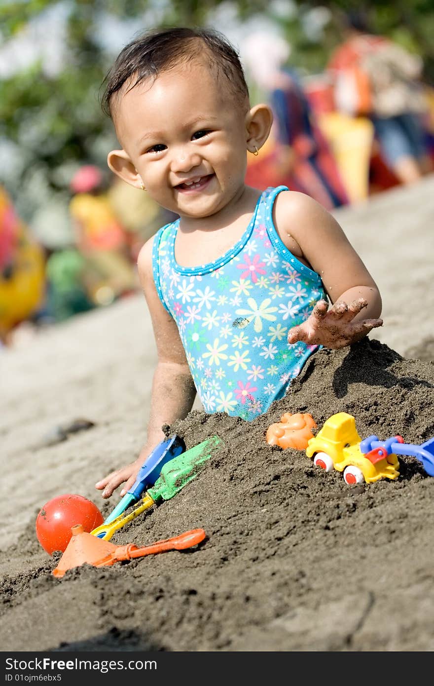 Cheerful asian baby girl enjoy playing with toys and sand on a hot sunny day at the beach. Cheerful asian baby girl enjoy playing with toys and sand on a hot sunny day at the beach