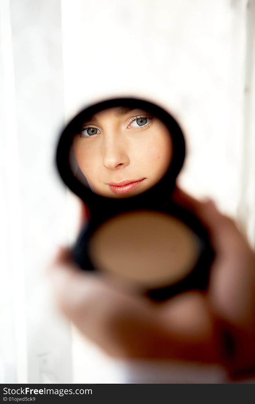 Young woman's face reflected in a mirror. Young woman's face reflected in a mirror