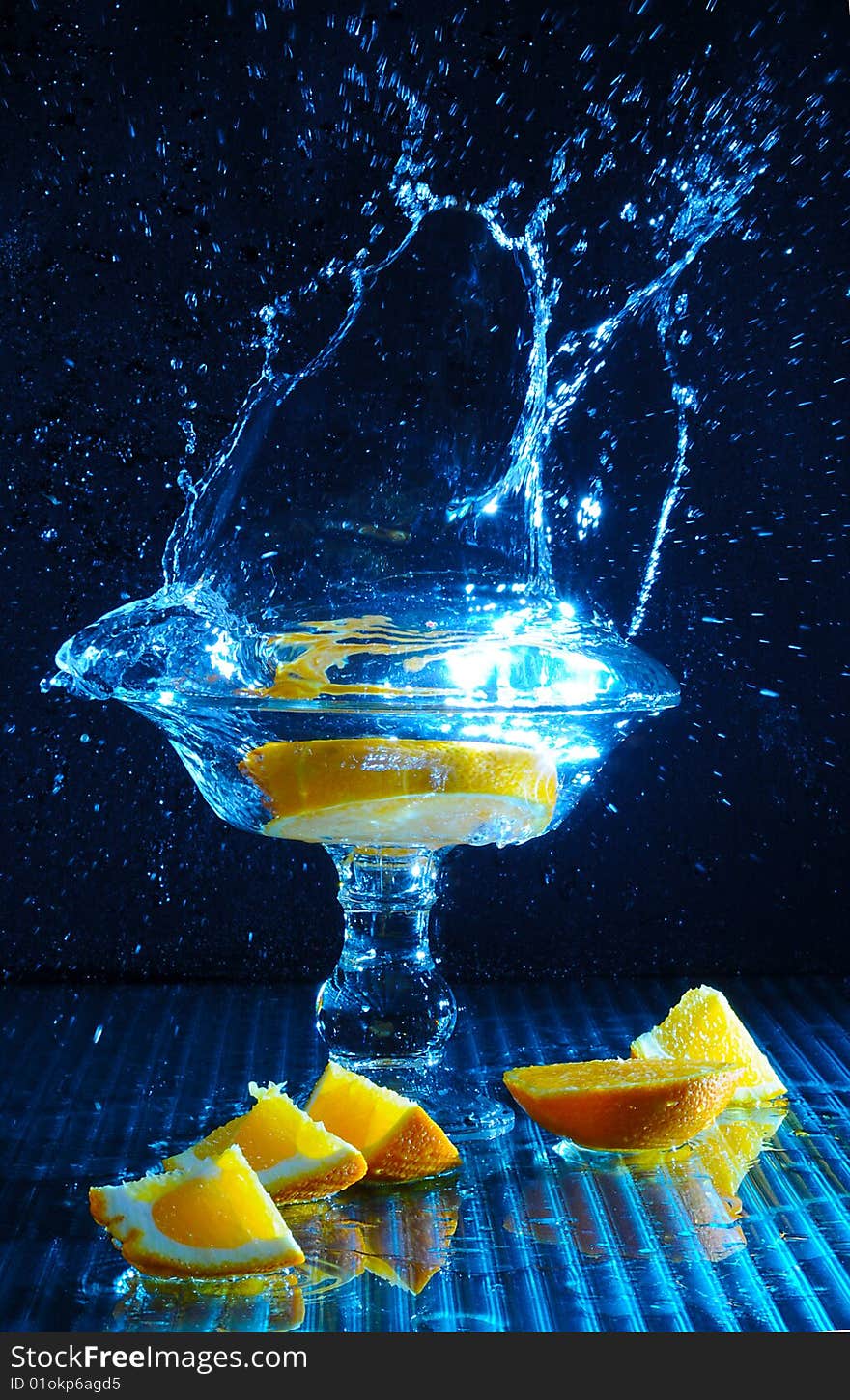 Color Photo freezing motion as orange slices are dropped in to a glass of water. Color Photo freezing motion as orange slices are dropped in to a glass of water.