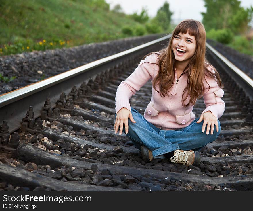 The young beautiful laughing girl sits on railway. The young beautiful laughing girl sits on railway