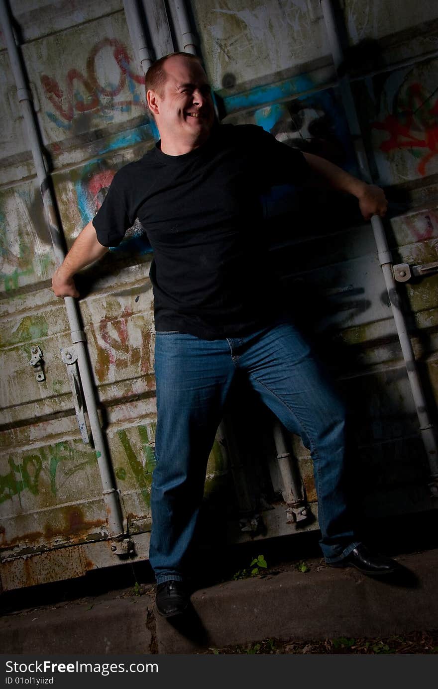 Powerful man expression portrait in a dark near container with graffiti