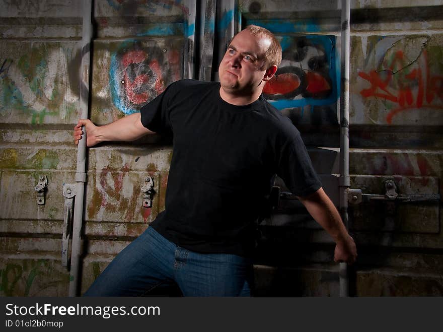 Powerful man expression portrait in a dark near container with graffiti