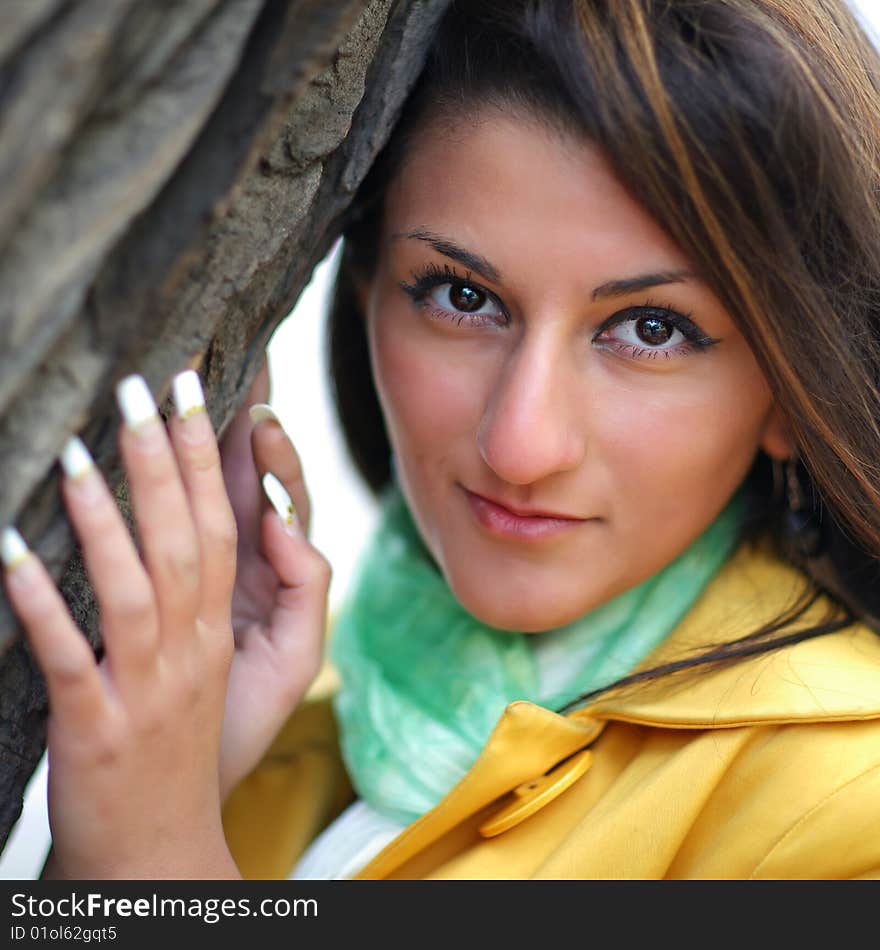 Portrait of the young beautiful woman at a tree close up