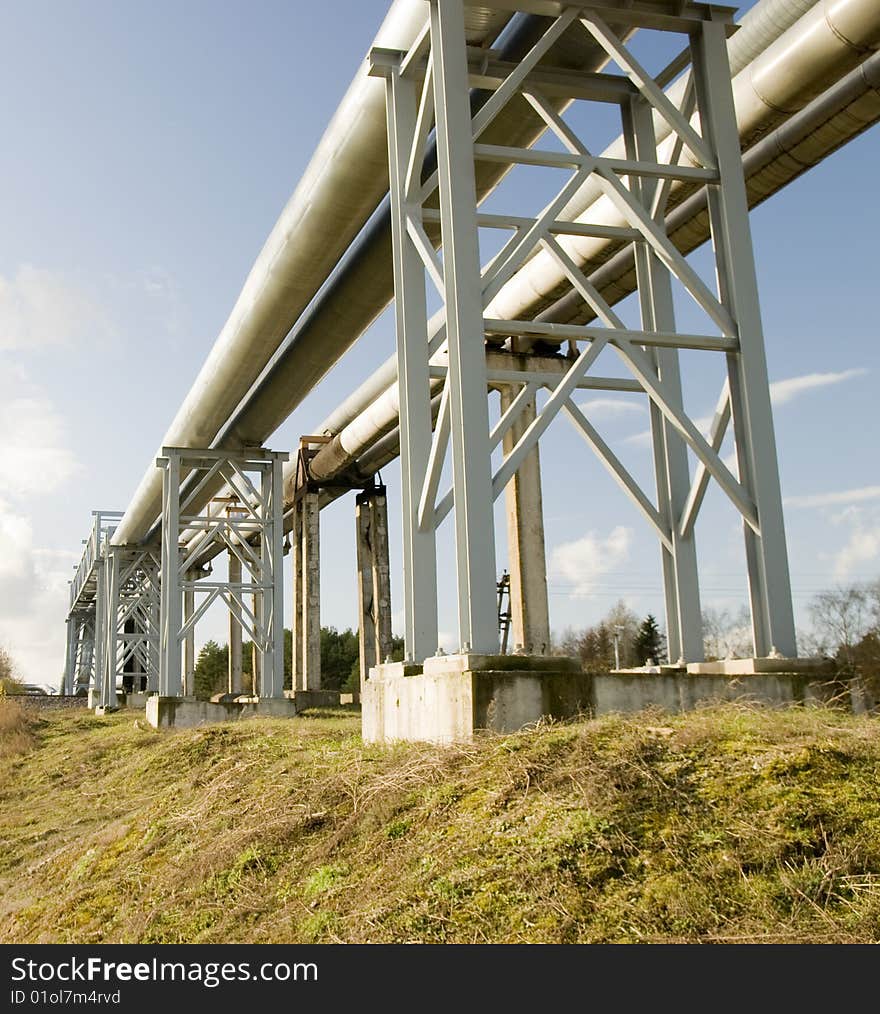 Industrial pipelines on pipe-bridge against blue sky. Industrial pipelines on pipe-bridge against blue sky.