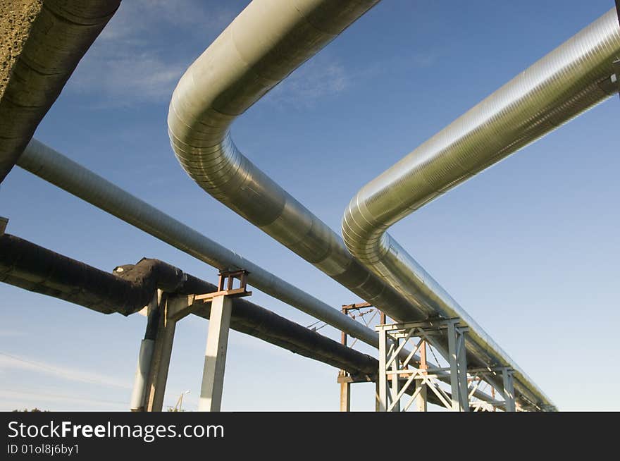 Industrial pipelines on pipe-bridge against blue sky. Industrial pipelines on pipe-bridge against blue sky.