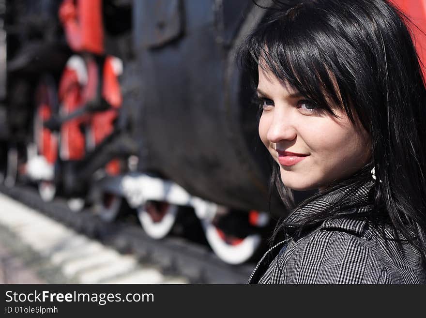 Portrait of the girl on a background of wheels of a steam locomotive. Portrait of the girl on a background of wheels of a steam locomotive