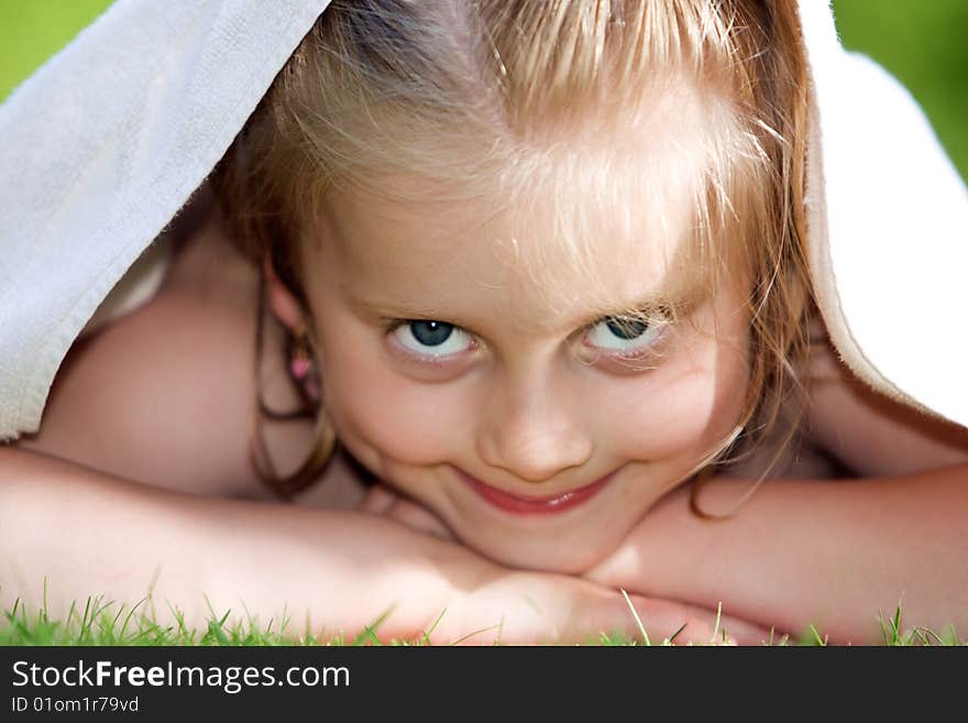 Young child is lying in lawn with towel on head. Young child is lying in lawn with towel on head