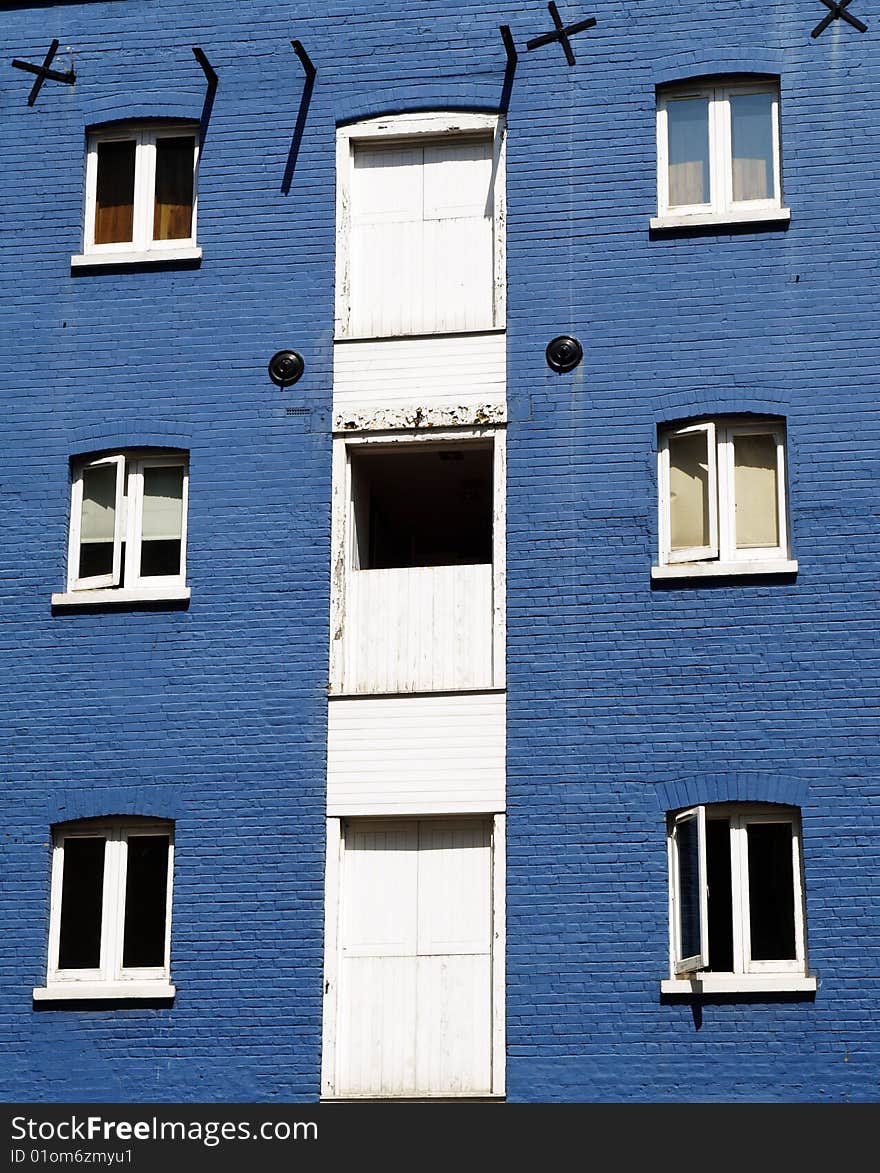 Contrasting white windows against a bright blue wall on an old building. Architectural details. Contrasting white windows against a bright blue wall on an old building. Architectural details.