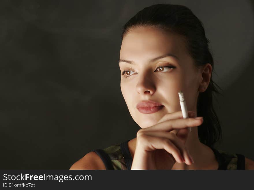 Romantic girl in camouflage with cigarette, studio shot